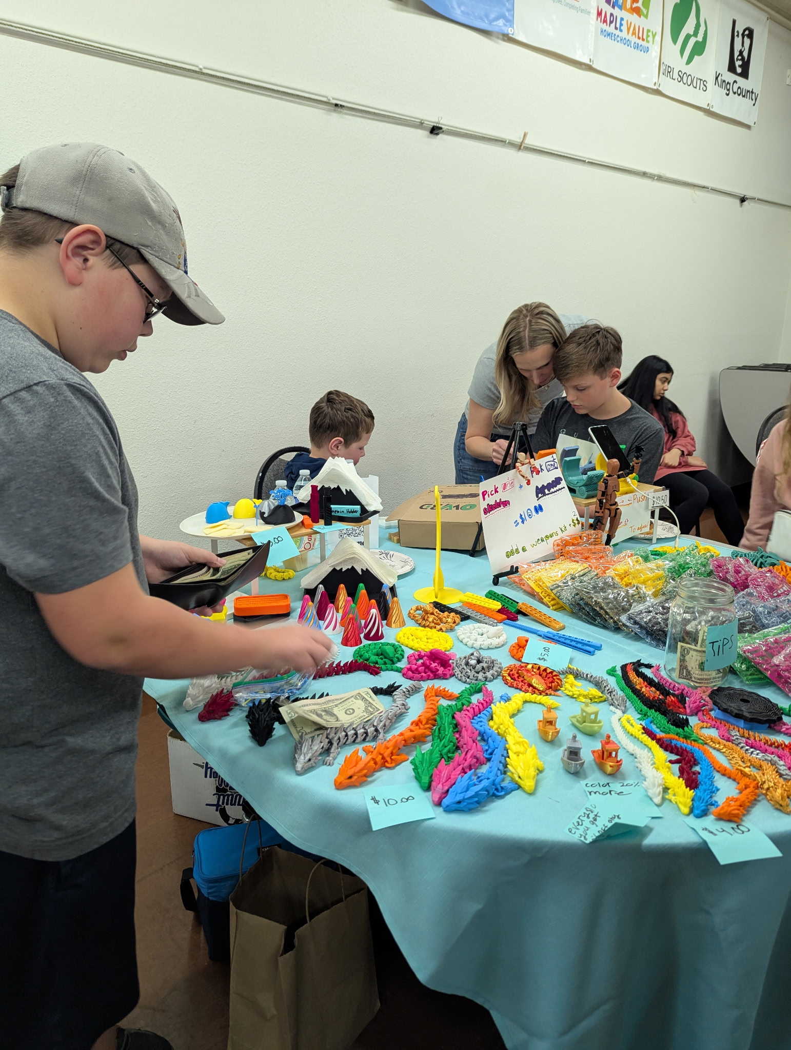Young entrepreneur's table of colorful 3D-printed dragons and toys for sale