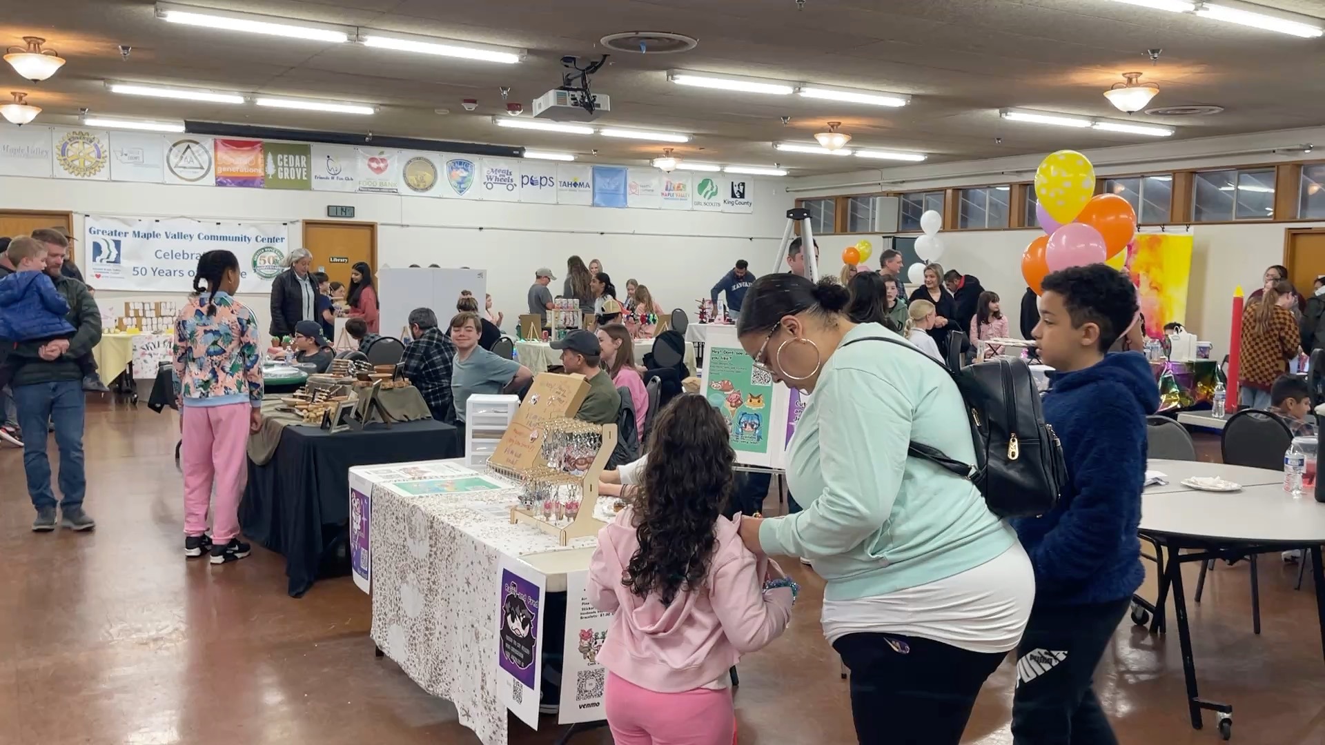 Visitors browsing craft and jewelry booths at the Maple Valley Children's Business Fair